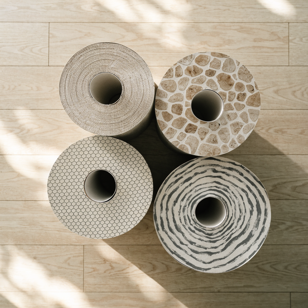Quatre rouleaux de papier peint debout sur un parquet clair